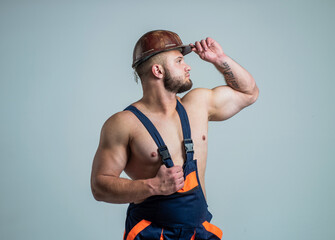 sexy builder in boilersuit. muscular man on construction site. handsome building worker in hard...