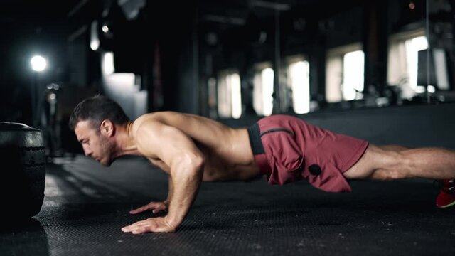 A handsome young muscular sportsman is doing exercise. A trainer performing push ups in the gym. Sport training. Concept of lifestyle fitness health and sports. Maximum focus and strength