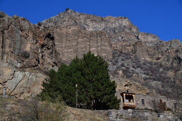 Panoramic view of high mountains and an old stone building with a beautiful balcony.