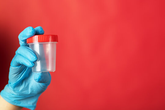 sperm donation, jar for male semen sample for fertilization and pregnancy, have children, in the hands of a doctor in a reproductive clinic on a red background