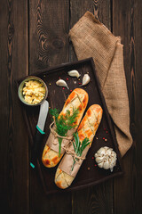Baguette with garlic butter and herbs, fried, on a brown wooden table, top view, rustic style, no...
