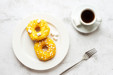 Two donuts with marshmallows and a cup of coffee