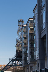 Fototapeta na wymiar A pier crane and facades of apartment buildings at the district Hammarby sjö sunny and snowy winter day in Stockholm