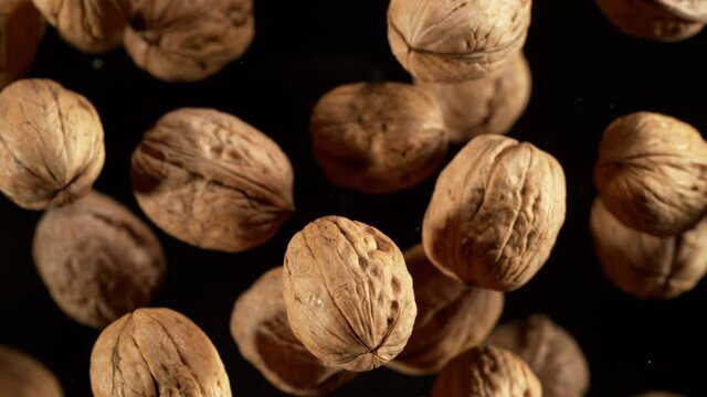 Super Slow Motion Detail Shot of Flying Whole Walnuts Towards Camera Isolated on Black at 1000fps.