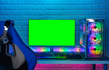 gaming chair and colorful bright rgb pc with keyboard mouse monitor green screen copy space in front of LED light brick stone wall. Computer playing hardware games background