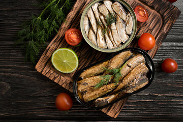 sprats in a can, fresh dill on wooden background
