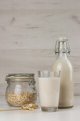 A bottle and a glass with dairy free oat milk and flakes in a jar