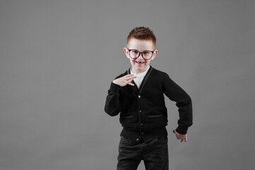 Little cute boy with glasses is smiling and having fun isolated on grey background. happy childhood. copy space
