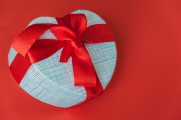 White festive box with red ribbon on red background.