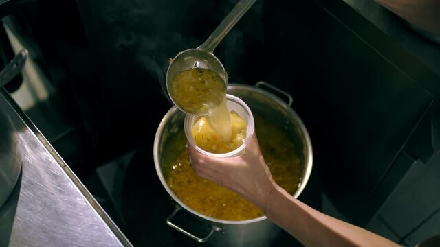 donations. cooking. charity. food delivery. Charities, community soup kitchens are serving free meals to poor and needy. the chef pours hot soup into a food container.