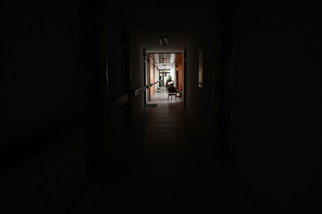 Fototapeta na wymiar A long dark hallway in the building. Unlit hallway in the school or hospital.