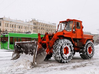 Tractor loader road service removes snow from the street