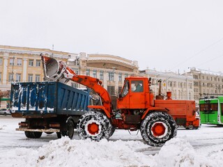 Tractor loading snow into a dump truck