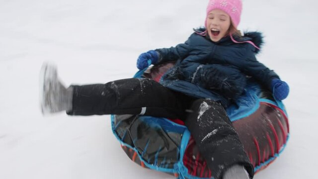 A cheerful happy girl on snow tube