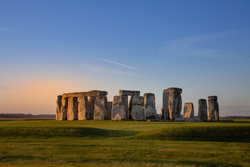 Stonehenge, a prehistoric monument during early morning. pink orange glow and blue sky