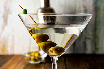 Close-up of a martini glass with olives on a light background.