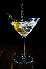 Vertical view of a martini glass with olives being served with the shot from above.