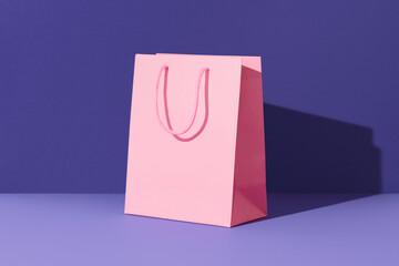 Pink paper shopping bag on purple background. Shopping sale delivery concept