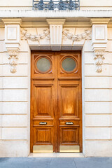 Paris, an ancient wooden door, beautiful decorated facade in the 11e arrondissement
