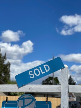 Sold sign is displayed on top of a for sale real estate sign