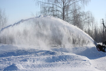 Clearing the road from snow with a snowplow on a sunny winter day