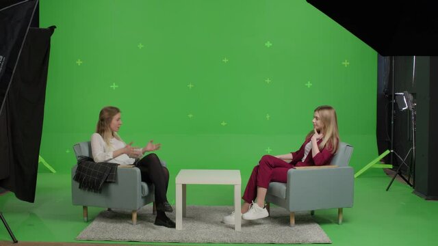 Young female patient and woman psychologist at psychotherapy session over green screen background. Youth talk show interview with a famous guest