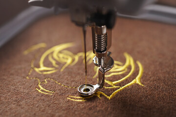 closeup on stitching of luxurious tiger head graphic on brown merino wool fabric with golden yarn...