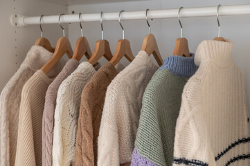 Warm beige wool pullover and knitwear and hanging in wardrobe