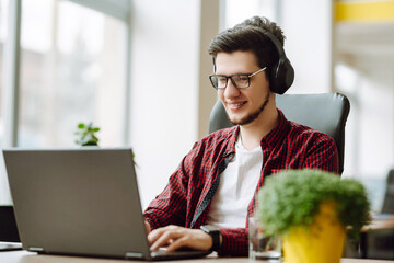 Education and working online. Young man with glasses working on laptop. Technology, Freelance, online course, remote work and lifestyle concept.
