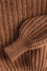 Warm caramel crochet jacket sleeve folded over itself. Vertical photo.