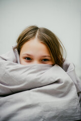 cheerful teen girl wrapped in a blanket