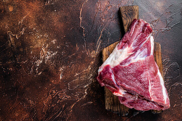 Raw lamb mutton thigh on butcher table. Dark background. Top view. Copy space