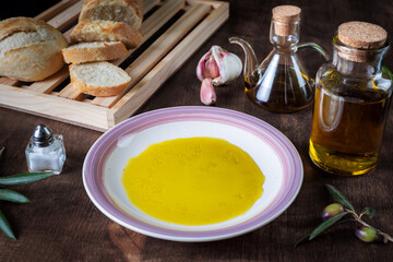 Dish with extra virgin olive oil together with a sliced bread bun.