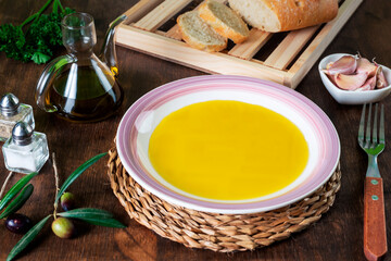 Dish with extra virgin olive oil together with a sliced bread bun.
