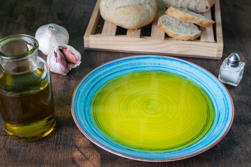 Dish with extra virgin olive oil together with a sliced bread bun.
