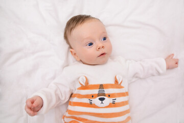 Baby boy with blue eyes in the morning in his bed. Portrait of a smiling baby in bed. Baby's morning, baby products concept.