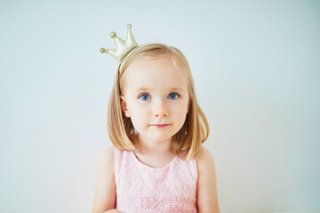 Adorable little girl in pink dress and golden crown dressed as princess