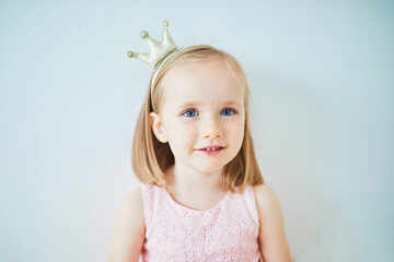 Adorable little girl in pink dress and golden crown dressed as princess