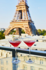 Two Cosmopolitan cocktails in traditional martini glasses with view to the Eiffel tower, Paris,...
