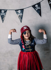 portrait of adorable little girl dressed as a pirate with eye patch and gesturing with strength