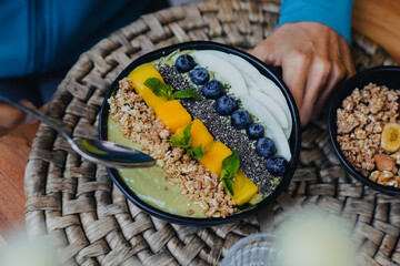 green vegan smoothie bowl with tropical fruits and granola like mango, spirulina, wheatgrass,...