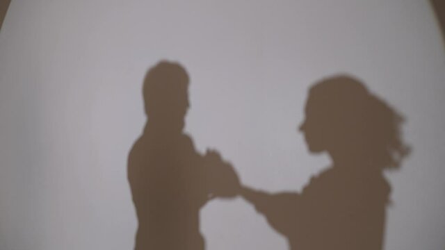 Dancing shadows on the wall guy and girl. Two silhouettes of young people. Reflection of a dancing pair of shadows on the wall.