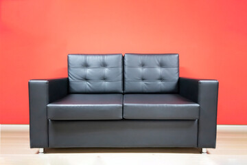 two seater or double black leather sofa on red wall