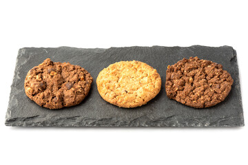 Three granola cookies of different varieties on a stone board for serving.