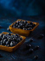 Two yellow square bowls with fresh blueberries on a dark blue background. Cooking, ingredients for various dishes and drinks, vitamins, antioxidants. Restaurant, hotel, culinary blog, advertising.