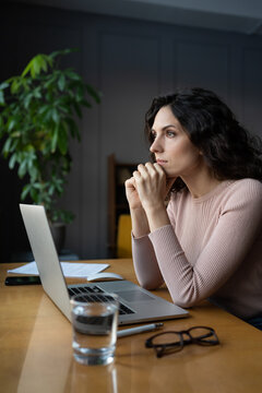 Distracted from work pensive young woman sit with laptop think of problem. Thoughtful unmotivated female look at window procrastinate suffer from lack of motivation working remotely on freelance task
