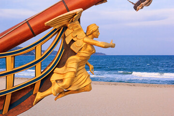 View of the bow and the figurehead of a stylized vintage sailboat close-up against the backdrop of the beach in Varna, on the Black Sea coast of Bulgaria - obrazy, fototapety, plakaty