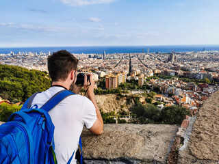 A young man photographing the view from Bunkers del Carmel over the city of Barcelona, Spain.