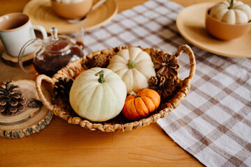 Fototapeta na wymiar basket with small decorative white and orange pumpkins and cones.