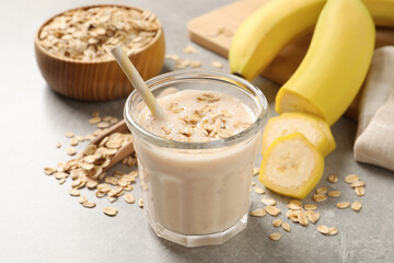 Glass of tasty banana smoothie with oatmeal on light grey table